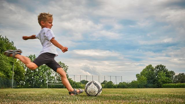 Chłopiec grający w piłkę nożną w ogrodzie