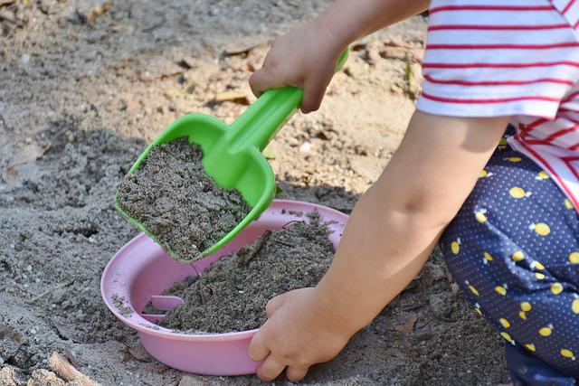 Dziecko bawiące się w piaskownicy w ogrodzie