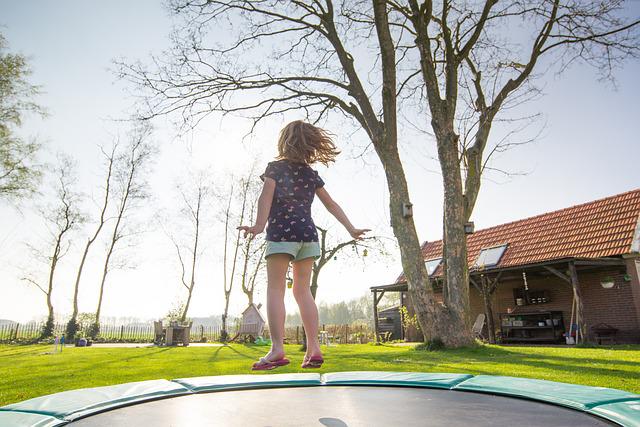 Dziewczynka skacząca na trampolinie w ogrodzie
